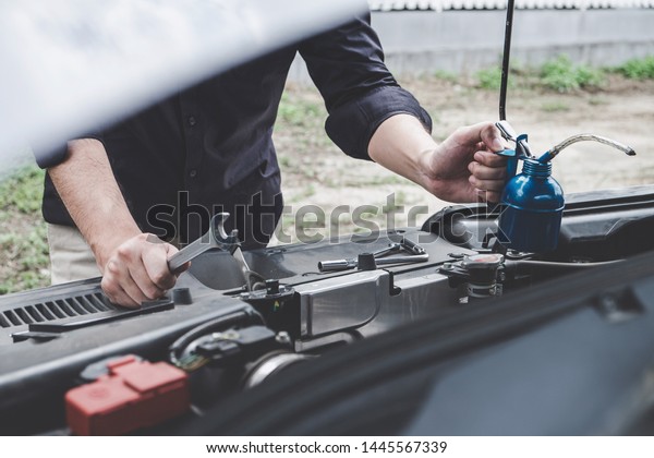 Services car\
engine machine concept, Automobile mechanic repairman hands\
repairing a car engine automotive workshop with a wrench and\
pouring oil, car service and\
maintenance.