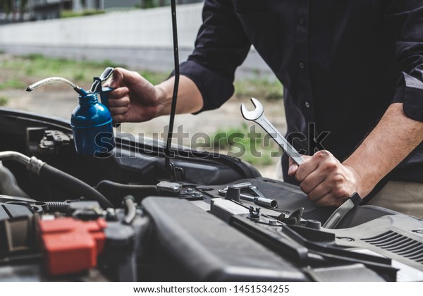 Services car\
engine machine concept, Automobile mechanic repairman hands\
repairing a car engine automotive workshop with a wrench and\
pouring oil, car service and\
maintenance.