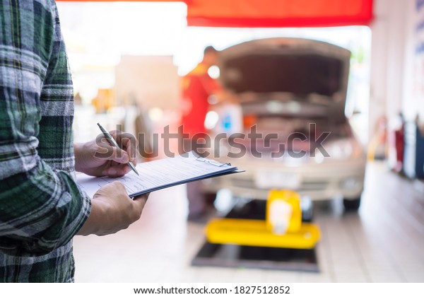 Services\
car engine machine concept, Automobile mechanic repairman checking\
a car engine with inspecting writing to the clipboard the checklist\
for repair machine, car service and\
maintenance.