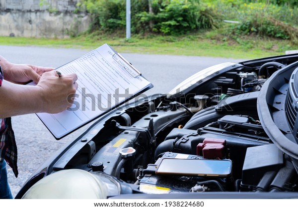 Services\
car engine machine concept, Automobile mechanic repairman checking\
a car engine with inspecting writing to the clipboard the checklist\
for repair machine, car service and\
maintenance.