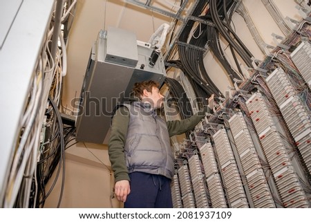Servicing the Automatic Telephone Station in the server room. The technician is laying communication lines by conducting internet telephony.