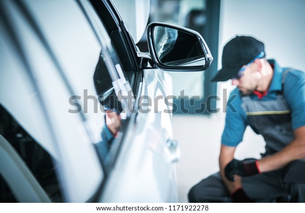 Servicing Modern Car Automotive Theme.\
Caucasian Auto Service Worker Checking on the\
Vehicle.