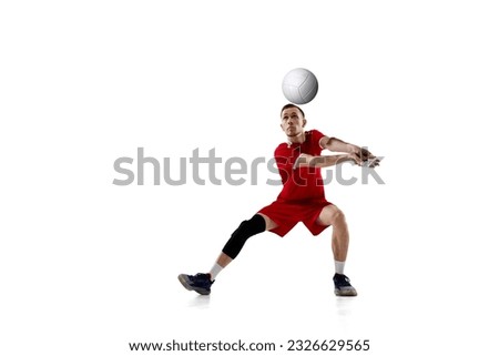 Serving ball. Young concentrated man, professional volleyball player in red uniform in motion against white studio background. Concept of sport, active lifestyle, health, dynamics, game, ad