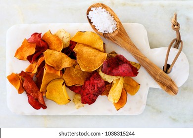 Serving Board Of Mixed Healthy Vegetable Chips With Sea Salt. Top View, Still Life On A White Stone Background.