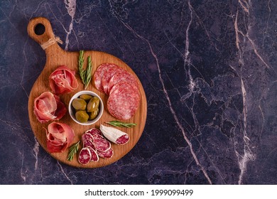 Serving board with a set of different meat snacks, top view.