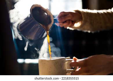 Sirviendo café de Cezve en taza de cerámica hecha a mano en la luz matutina con vapor 