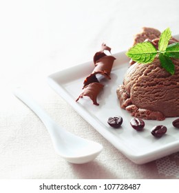 Serving of coffee icecream garnished with coiled chocolate and freshly roasted beans