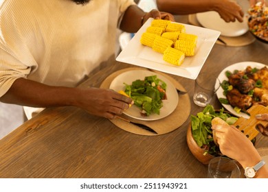 Serving corn on cob, people enjoying meal together at dining table. mealtime, communal, gathering, food, social, togetherness - Powered by Shutterstock