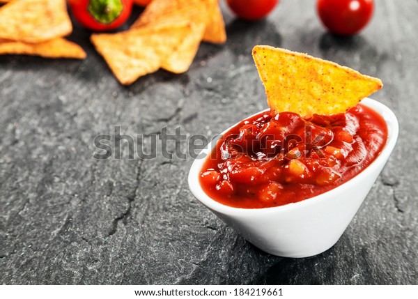 Serving of hot spicy salsa sauce made with\
tomato and chili peppers in a bowl with corn tortillas or nachos to\
dip for a savory\
appetizer