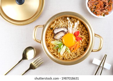 Serving a Korean style instant noodle, Ramyeon or Ramyun with spicy flavour topped with egg yolk, chilli, vegetables and kimchi in a traditional Korean noodle pot. - Shutterstock ID 1987018631