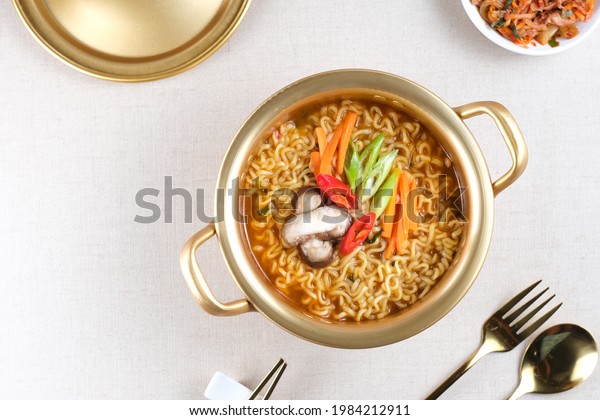 Serving a Korean style\
instant noodle, Ramyeon or Ramyun with spicy flavour topped with\
egg yolk, chilli, vegetables and kimchi in a traditional Korean\
noodle pot.