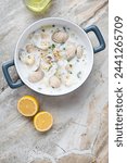 Serving pan with new england clam chowder on a light-grey granite background, vertical shot with space, above view