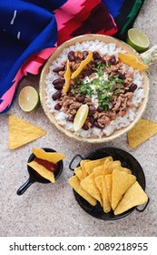 Serving Pan With Tex-mex Chilli Con Carne, White Rice And Nachos, Above View On A Beige Marble Background With Multicolored Poncho