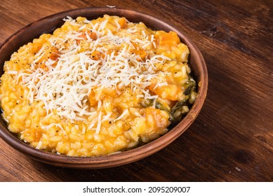 Serving of pumpkin risotto in a plate sprinkled with grated parmesan cheese, close-up, copy space