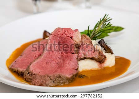 Serving of rare prime rib of beef with mashed potatoes and garnished with rosemary