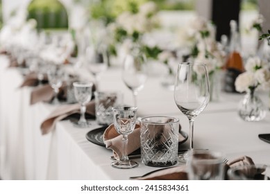 Serving, setting table in the backyard. Plate and glass, stack, wineglass, luxury rich decor. Wedding set up, dinner table reception on terrace. Birthday, baptism, event. Closeup details of interior.