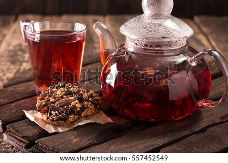 Serving table for breakfast, red tea in teapot and granola on a wooden table