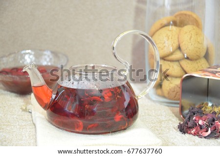Serving table for breakfast, red tea in teapot. tea leaves, hibiscus