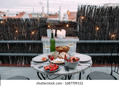 Serving A Table For Two Persons On The Nice Terrace During Sunset To Spend Time Together For Couple In Love Romantic Date With Food Barbeque White Wine Cozy Natural Day Light Warm Lams And Candle