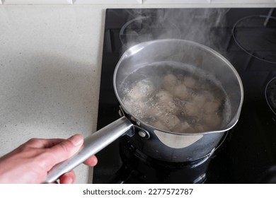 Serving of traditional Russian dough and meat dish in a boiling water in a pot. Dumplings filled with meat, cheese and mushrooms. Popular Eastern European food