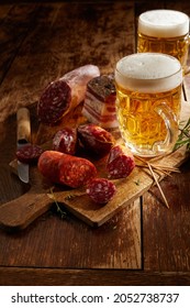 Serving for two with ice cold beers and cold meat selection on a rustic or vintage wooden cutting board in shadowy light in a rustic pub or tavern - Shutterstock ID 2052738737