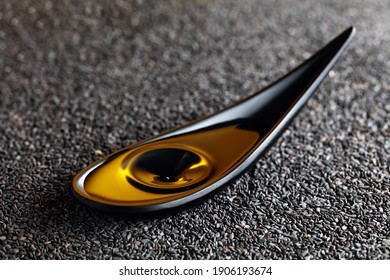 Sesame Oil And Black Sesame Seeds. A Drop Of Oil Fall In A Small Black Dish.