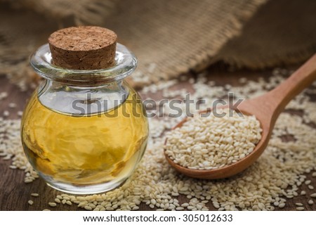 Sesame oil in glass jar and sesame seeds on wooden spoon