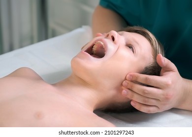 Session of craniosacral therapy, cure of teen boy's jaw by a doctor therapist. Craniosacral therapist touches the boy's cheeks and checks the correctness of the jaws at the hospital.