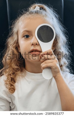 Session of testing the sight sharpness. Little girl is checking vision in the ophthalmologist cabinet.