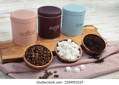 Set of 3 Storage Tins for housing teas, coffee and sugar. Set of three Storage Jars.Three pastel colorful kitchen storage jars for tea, sugar and coffee arranged in a row on wooden table.