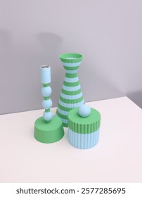 A set of 3d printed design objects with a striped vase, a candle holder and a cylinder box on white table