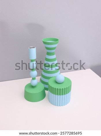 A set of 3d printed design objects with a striped vase, a candle holder and a cylinder box on white table