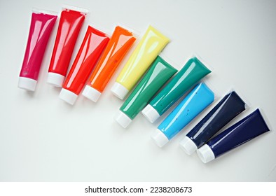 A set of acrylic, gouache, watercolor, oil paints on a white background.Plastic transparent tubes with paint in the colors of the rainbow: red, orange, yellow, green, blue, blue, purple.
