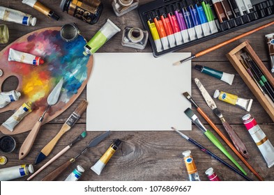 Set of artist accessories collection. Canvas, tube of oil paint, art brushes, palette knife lying on the wood table. Artist workshop background. - Shutterstock ID 1076869667