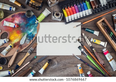 Set of artist accessories collection. Canvas, tube of oil paint, art brushes, palette knife lying on the wood table. Artist workshop background.