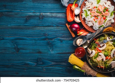 Set of Asian cuisine. Risotto with shrimps noodles with vegetables. Seafood. On a wooden texture background. Top view. Free space.