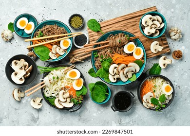A set of Asian dishes with noodles. Udon and soba noodles. On a concrete gray background. Top view.