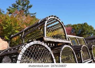 Set aside for storage, a large stack of weathered and faded vintage, wooden lobster traps sit in the sun in Maine.