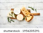 Set or assortment cheeses. Suluguni with spice, camembert, blue cheese, parmesan, maasdam, brie cheese with rosemary and pepper.  Top view. On white wooden old background. Free copy space.