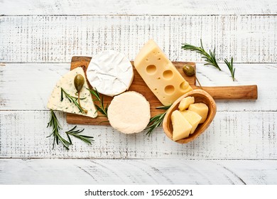 Fijar o surtir quesos. Suluguni con especias, camembert, queso azul, parmesano, maasdam, queso brie con romero y pimienta.  Vista superior. Sobre un fondo antiguo de madera blanca. Espacio libre de copia.