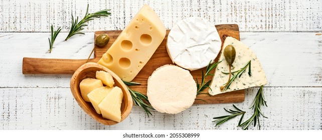 Set or assortment cheeses. Suluguni with spice, camembert, blue cheese, parmesan, maasdam, brie cheese with rosemary and pepper. On white wooden old background. Top view. Copy space. Banner. - Powered by Shutterstock