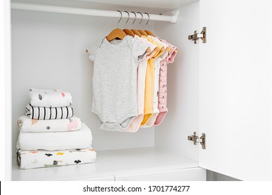 Set Of Baby Bodysuits For A Newborn Girl And Boy On Hangers In White Wardrobe. Motherhood, Cleaning Home Kids Wardrobe. Minimal Fashion Concept.