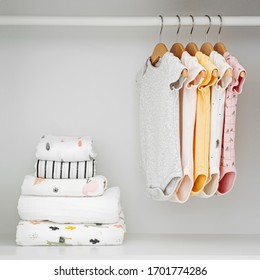 Set Of Baby Bodysuits For A Newborn Girl And Boy On Hangers In White Wardrobe. Motherhood, Cleaning Home Kids Wardrobe. Minimal Fashion Concept.