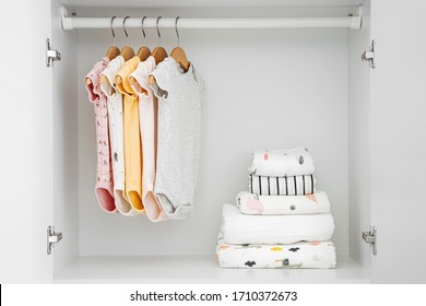 Set Of Baby Bodysuits For A Newborn Girl And Boy On Hangers In White Wardrobe. Motherhood, Cleaning Home Kids Wardrobe. Minimal Fashion Concept.