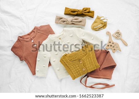 Set of  baby rompers, hat,  hairband and  knitted jumper on white bed. Fashion  baby clothes and accessories. Flat lay, top view