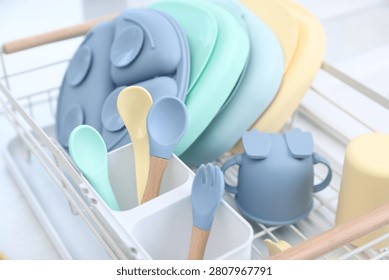 Set of baby tableware in drying rack on countertop in kitchen, closeup