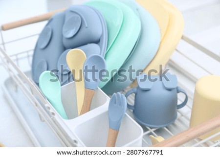 Set of baby tableware in drying rack on countertop in kitchen, closeup