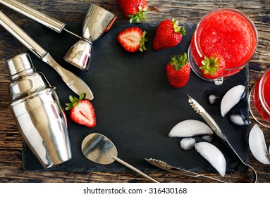 Set of bar accessories and ingredients for making a cocktails arranged on a wooden background with black board for copy space