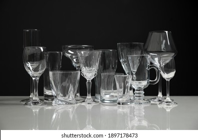 Set Of Bar Glassware On White Table Against Black Background