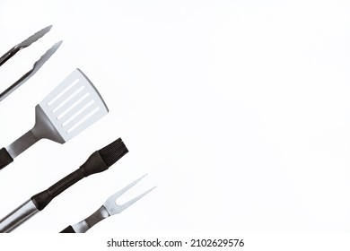 Set with barbecue utensils on white background. Stainless steel spatula, oil brush, tongs, fork for bbq. Copy space.